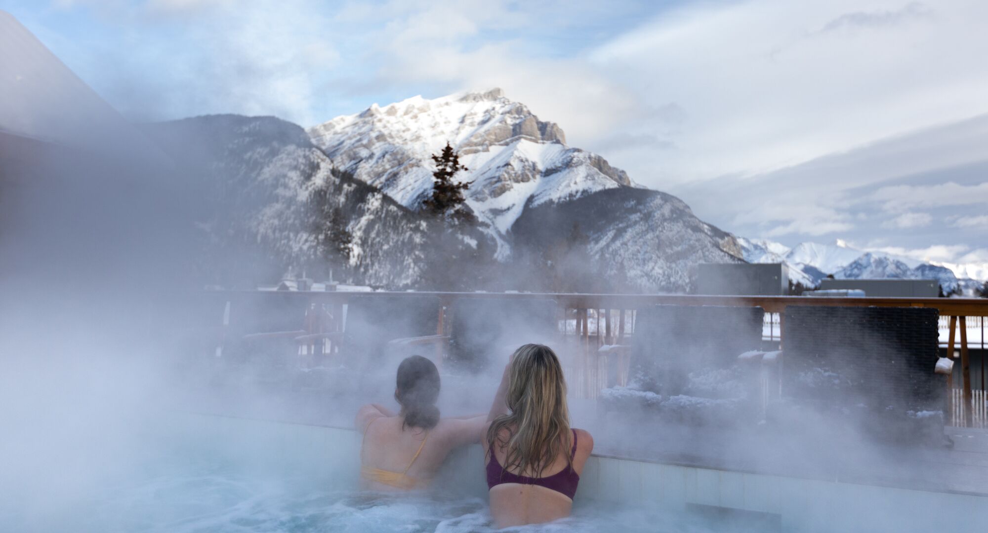 friends enjoy the rooftop, outdoor hot tub at the Moose Hotel in winter.